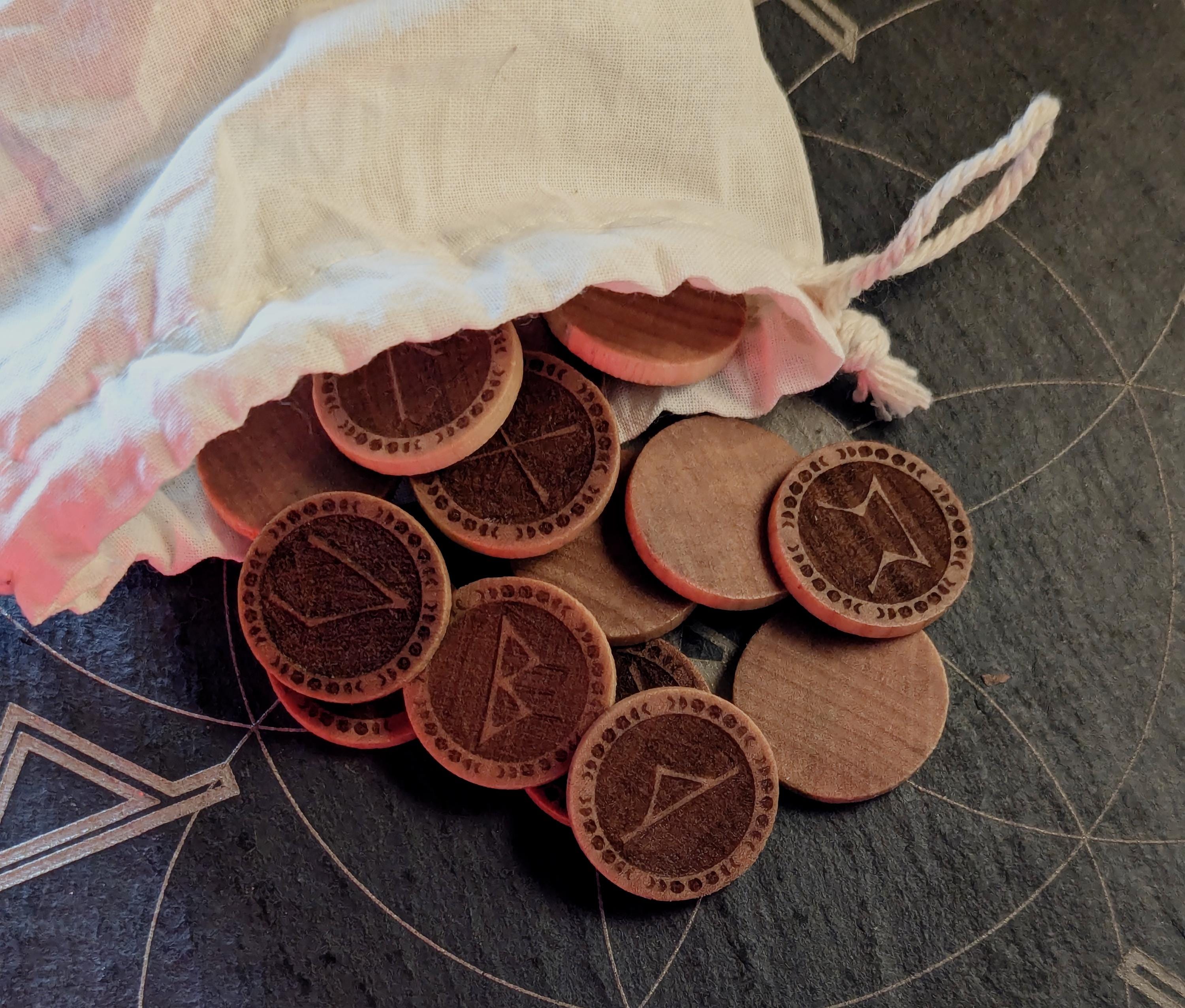 Elder Futhark Rune Set, hadcrafted from hardwood in Canada, on a stone surface with a drawstring bag.